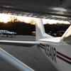 Small aircraft sitting on an airport ramp at sunset.