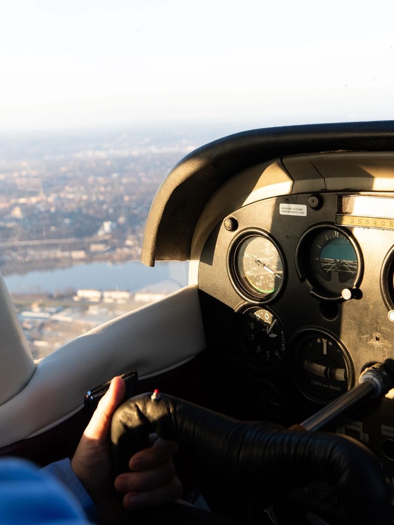 A man in a blue shirt controls a small aircraft in flight.