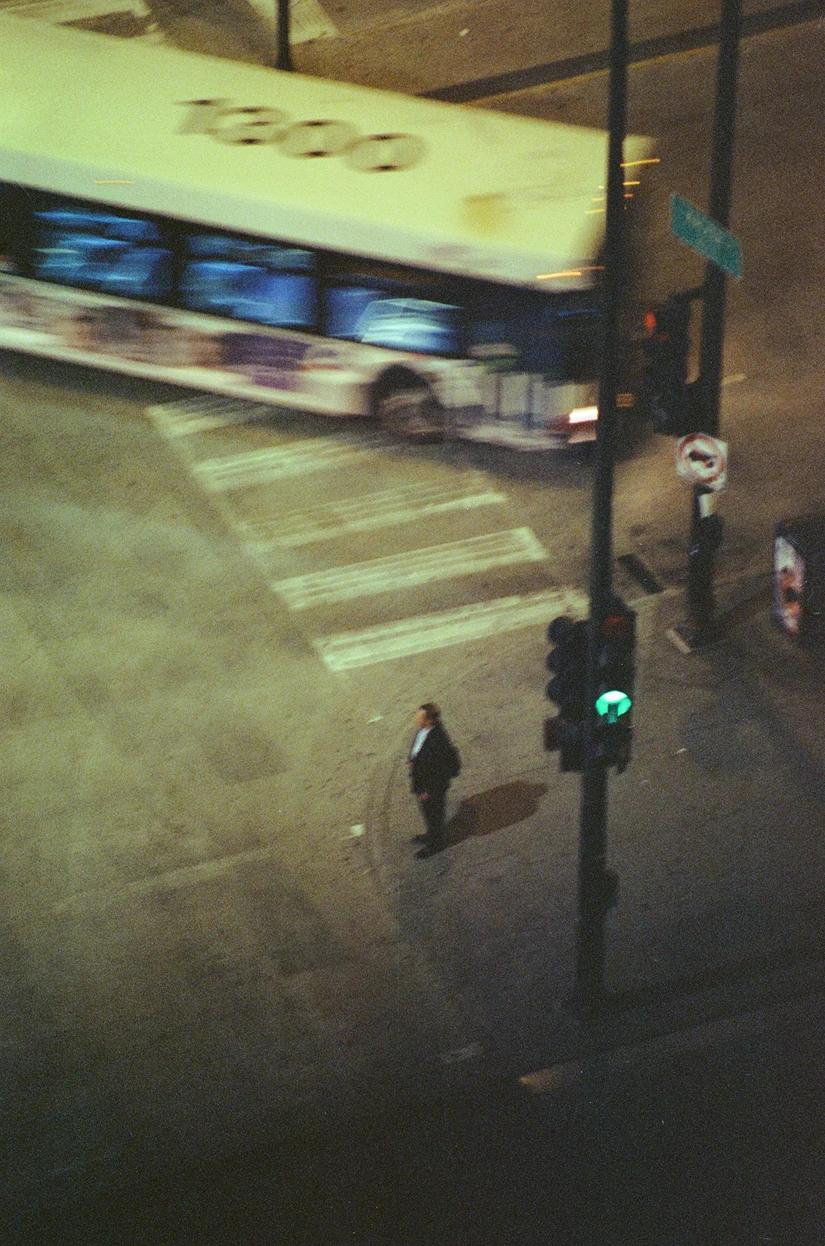 a bus turning and man waiting to cross the street in the middle of the night