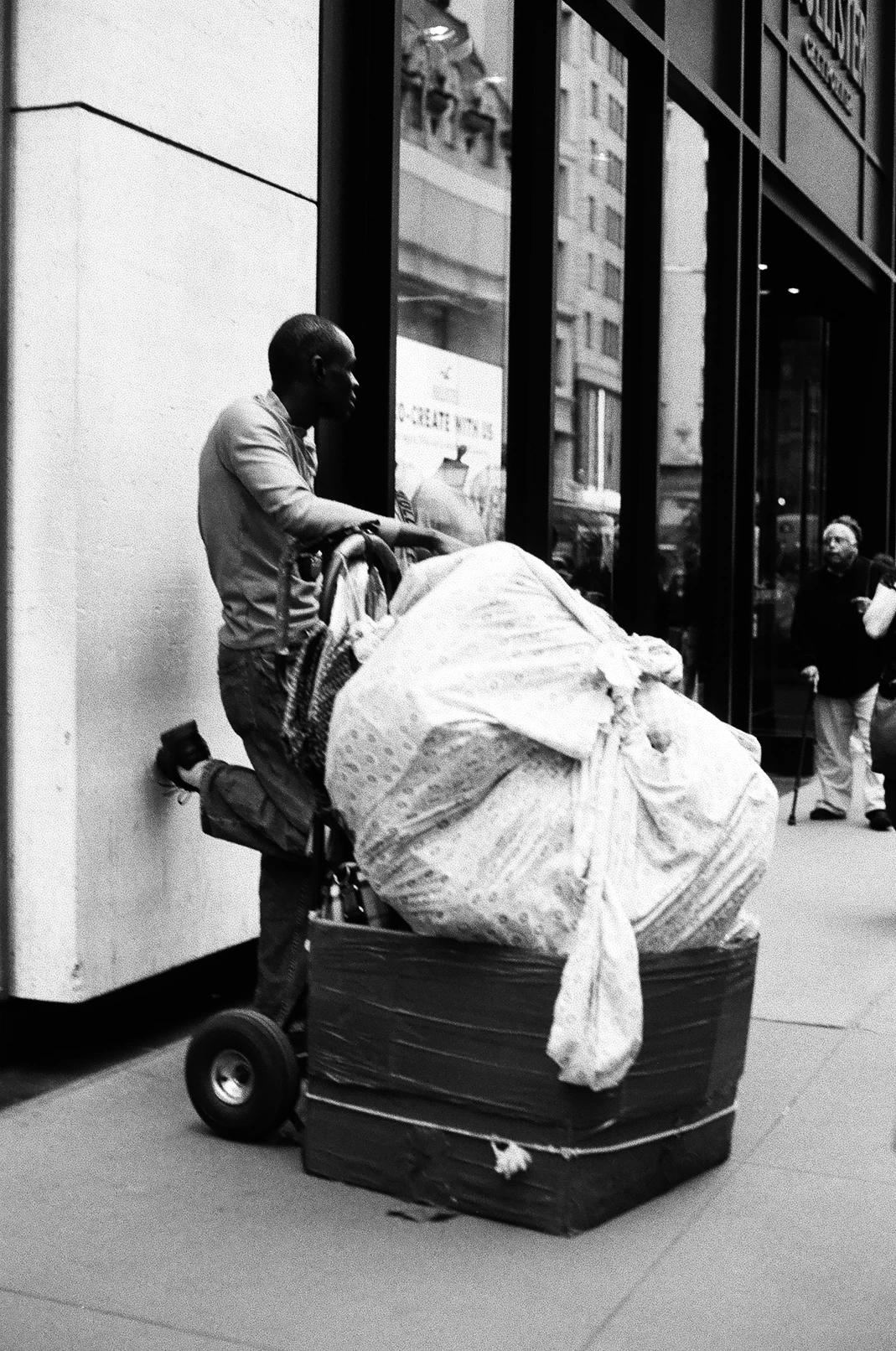 Man leaning against wall with a lot of stuff in the middle of the street