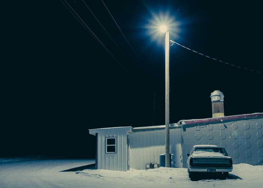 a car is parked by a house and street light on a snowy night