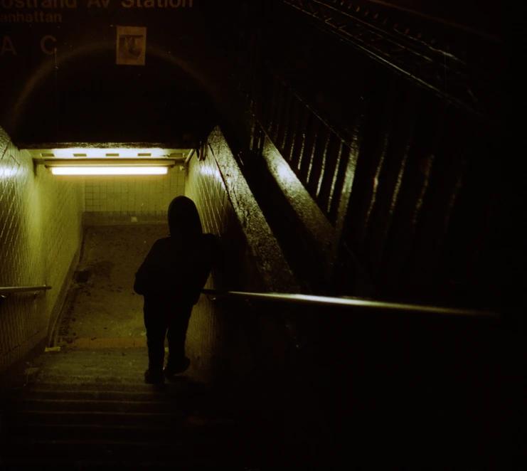 Man leaning against rail on a staircase leading to a subway station