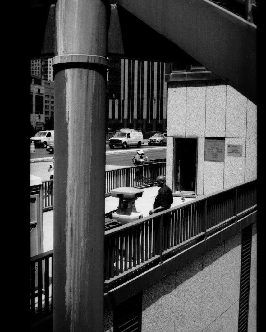 Man leaning against rail with his back while looking onto the street
