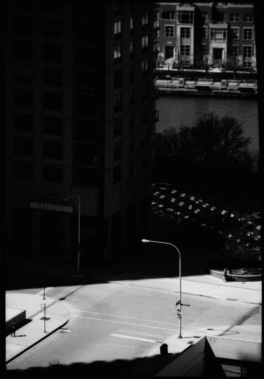 an empty city street half covered in shadow with a river in the background