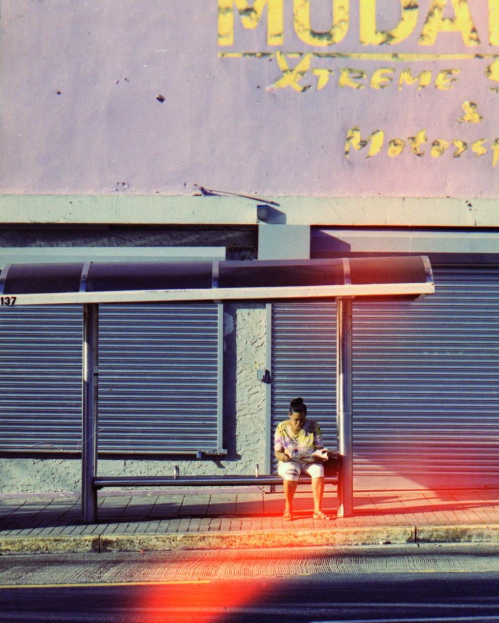 Lady waiting on the bus in the middle of the day
