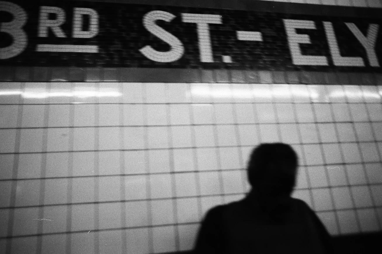 A person covered in shadow in a subway station