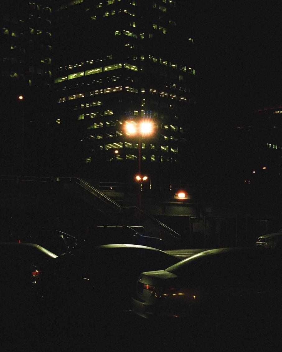 the lights from a skyscraper seen from a parking lot at night