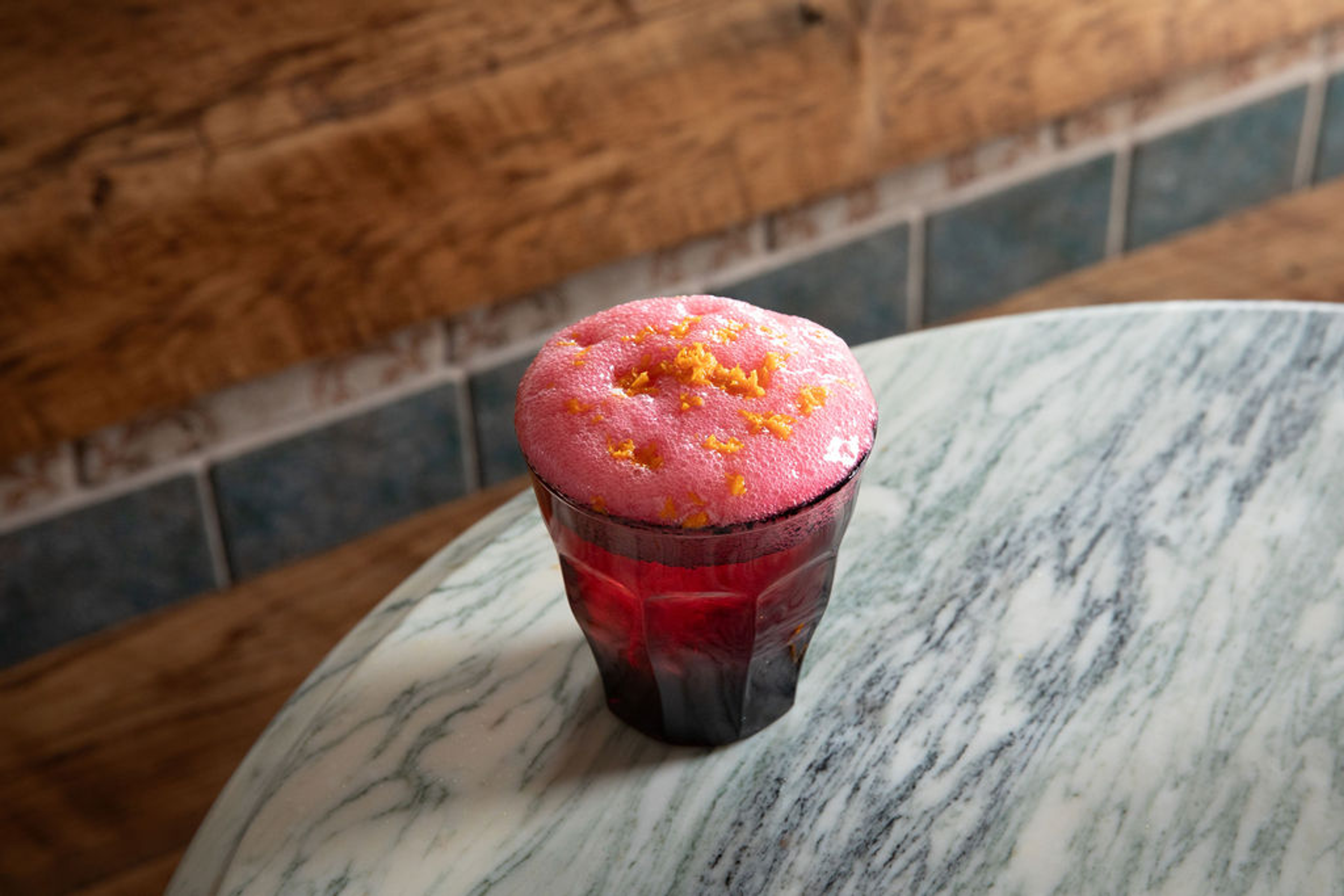 festive hibiscus mezcal cocktail in glass with foam