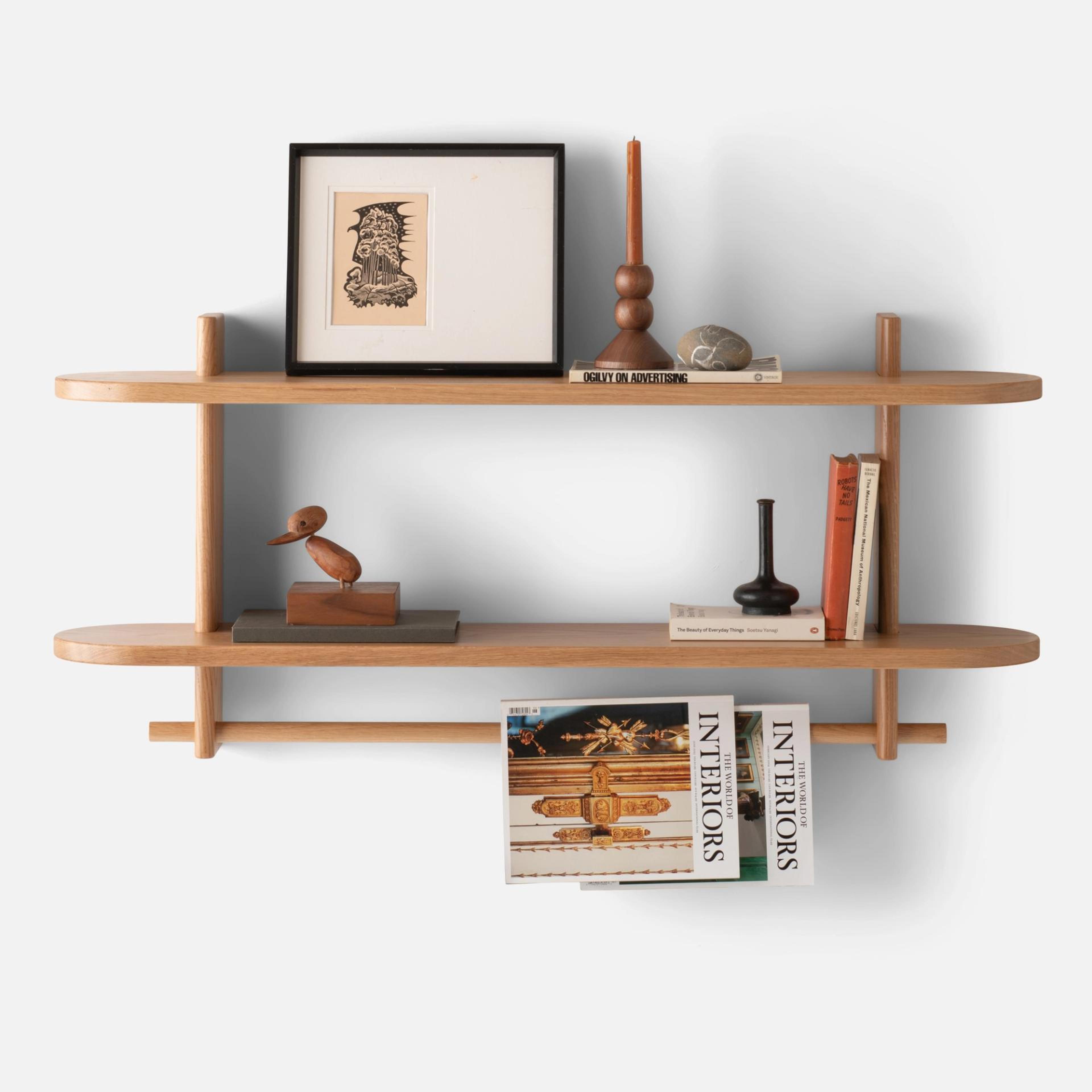 open small wooden shelf on white wall with picture frame, candle sticks, paperweight, and books