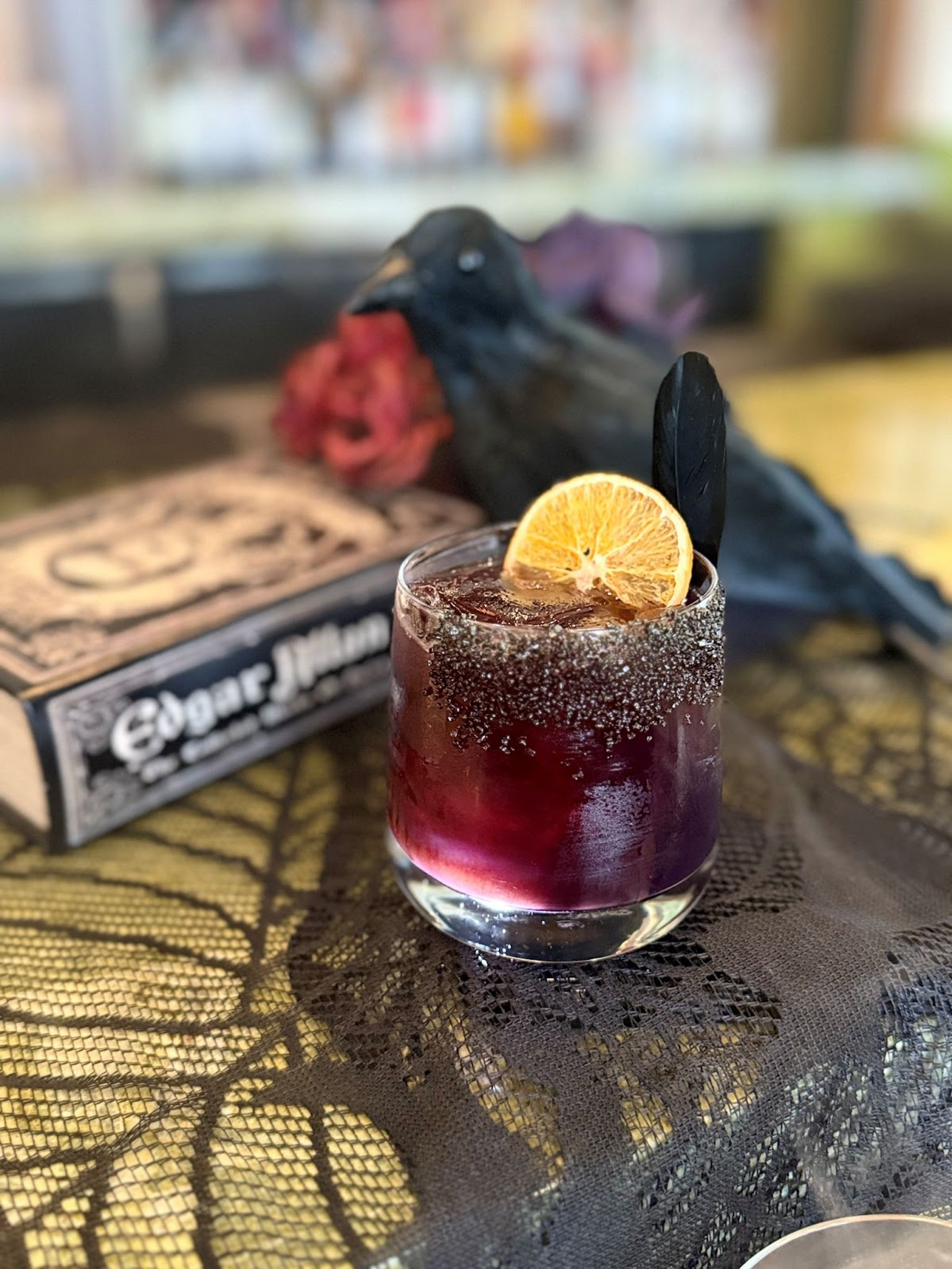 dark pink drink in cocktail glass with black salt rim and lime garnish