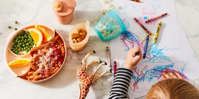 kid drawing on paper while eating dinner