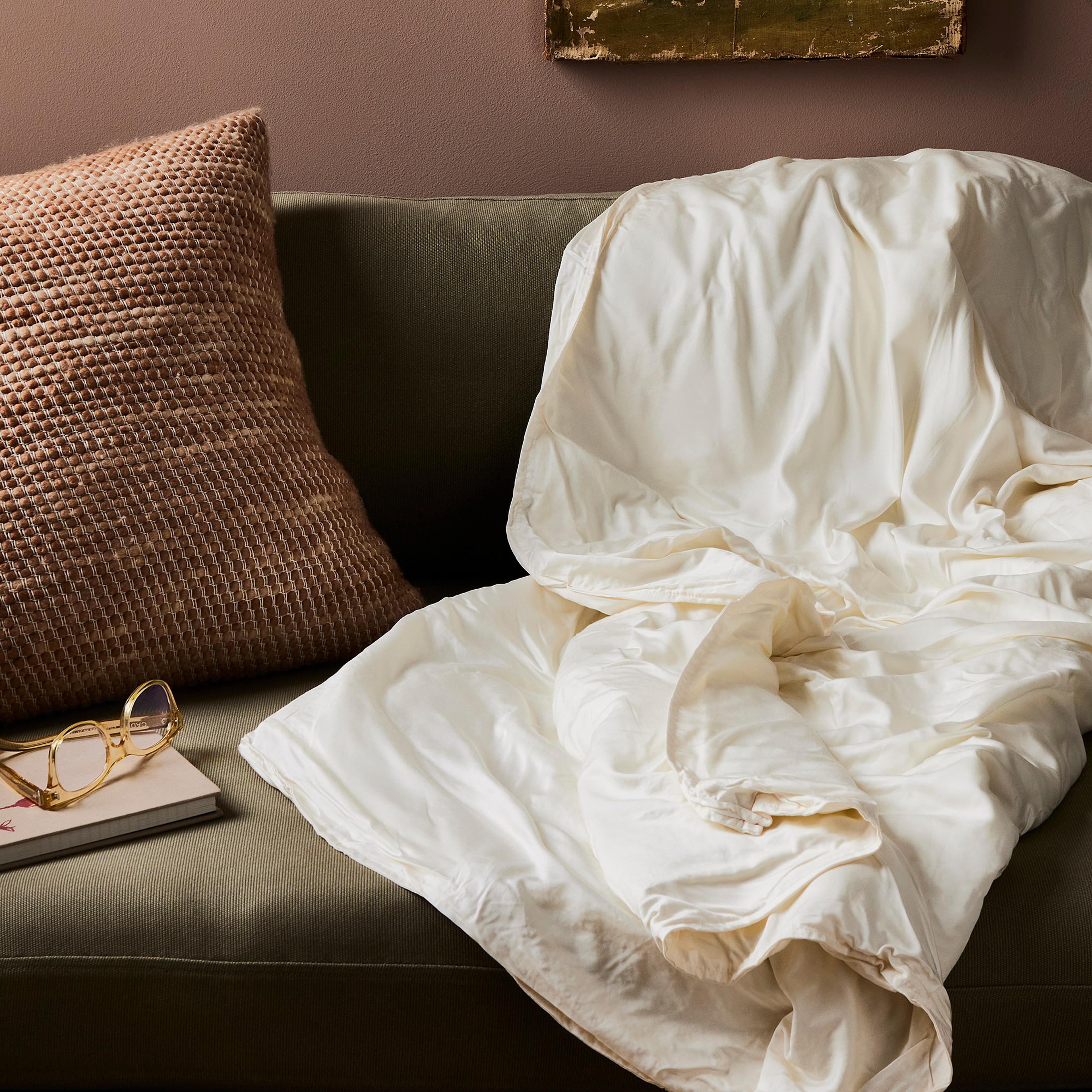 A cozy chair with a blanket on it.