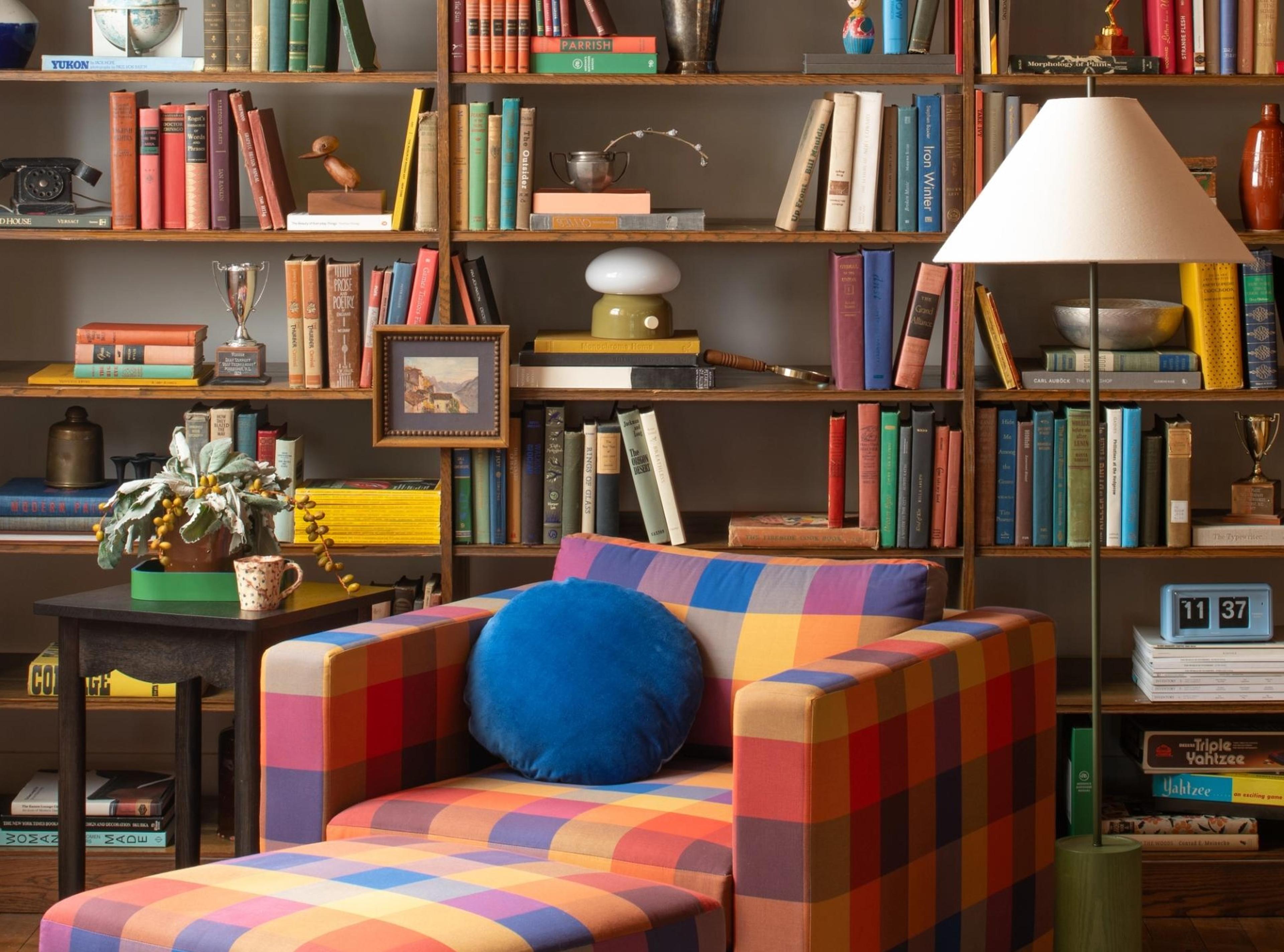 living with rainbow chair and styled bookshelves with various thrifted items, books, candle holders, etc