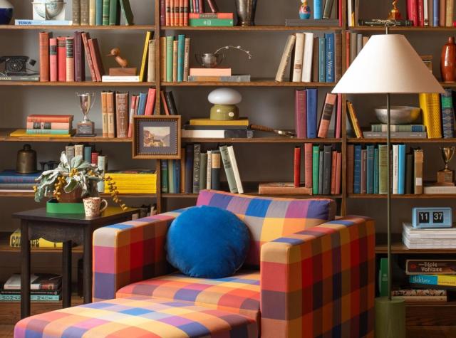 living with rainbow chair and styled bookshelves with various thrifted items, books, candle holders, etc