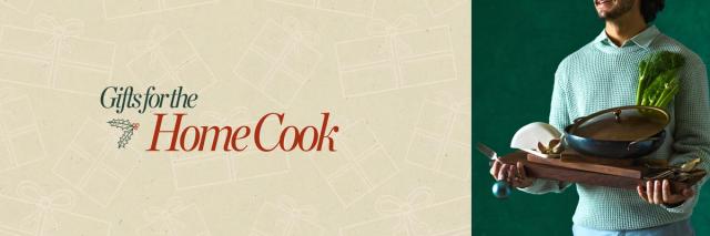 person wearing a sweater holding trays, cookware, and more cooking gifts