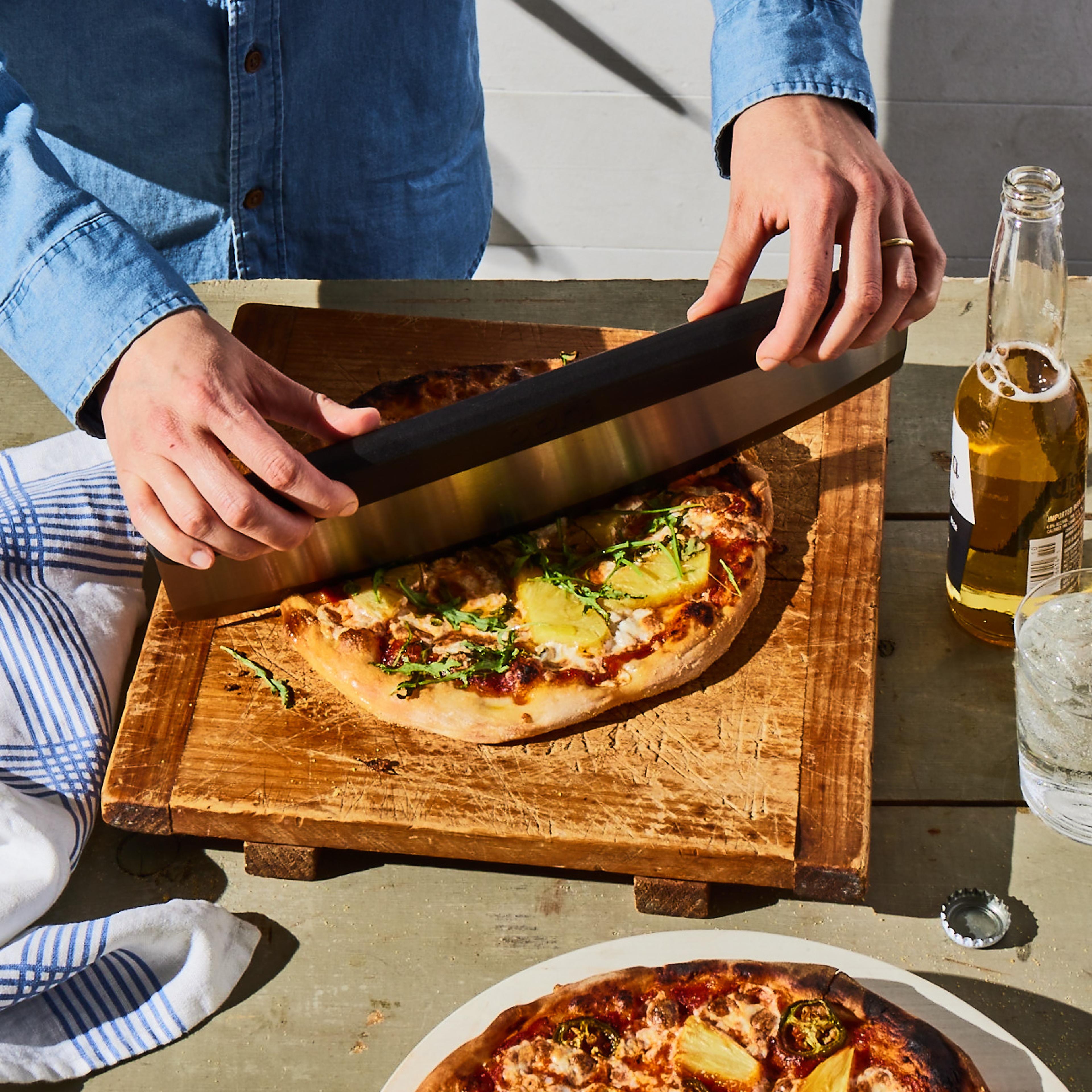 person cutting personal homemade pizza