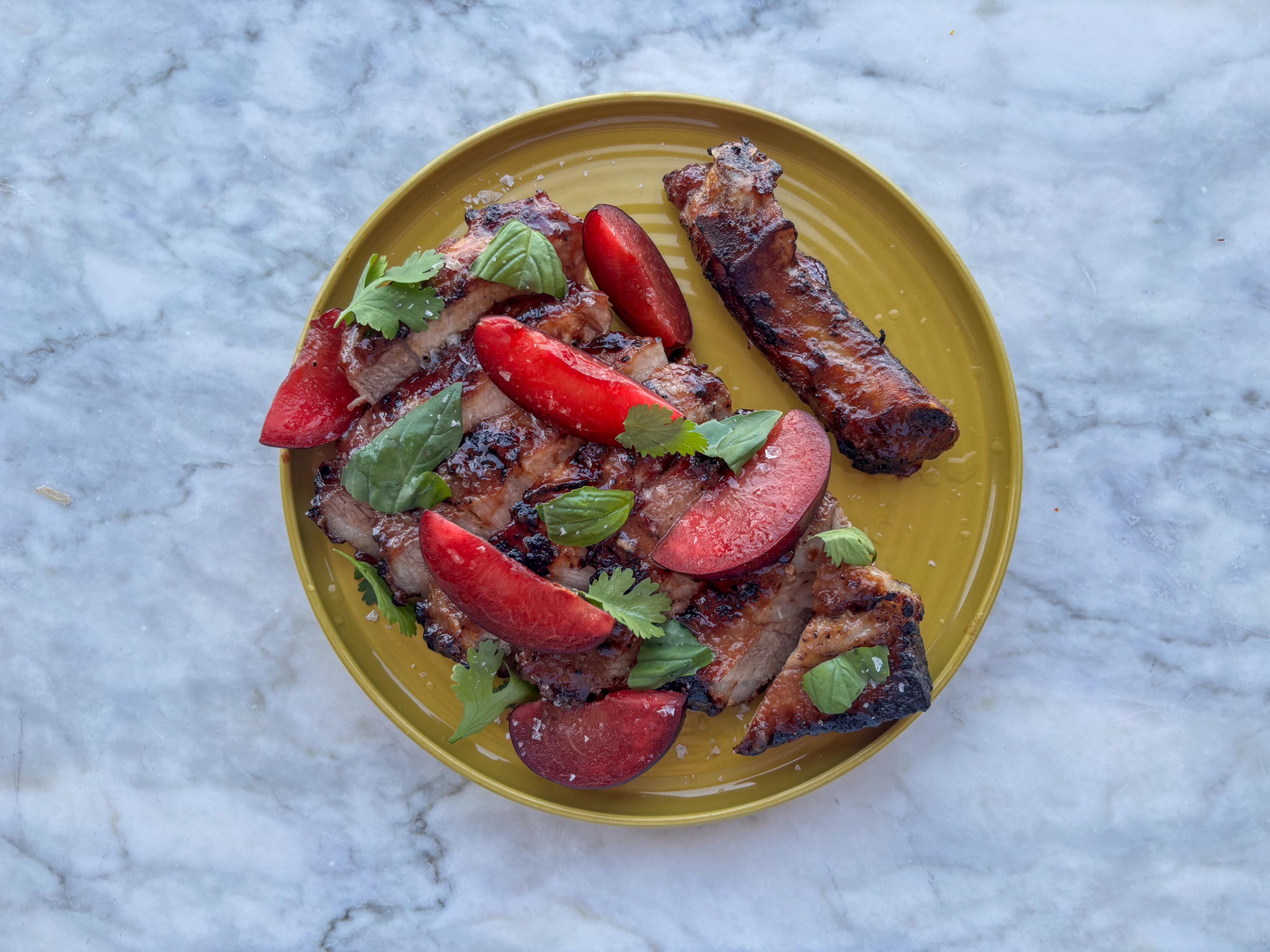 plum glazed pork plated with fresh plums and herbs