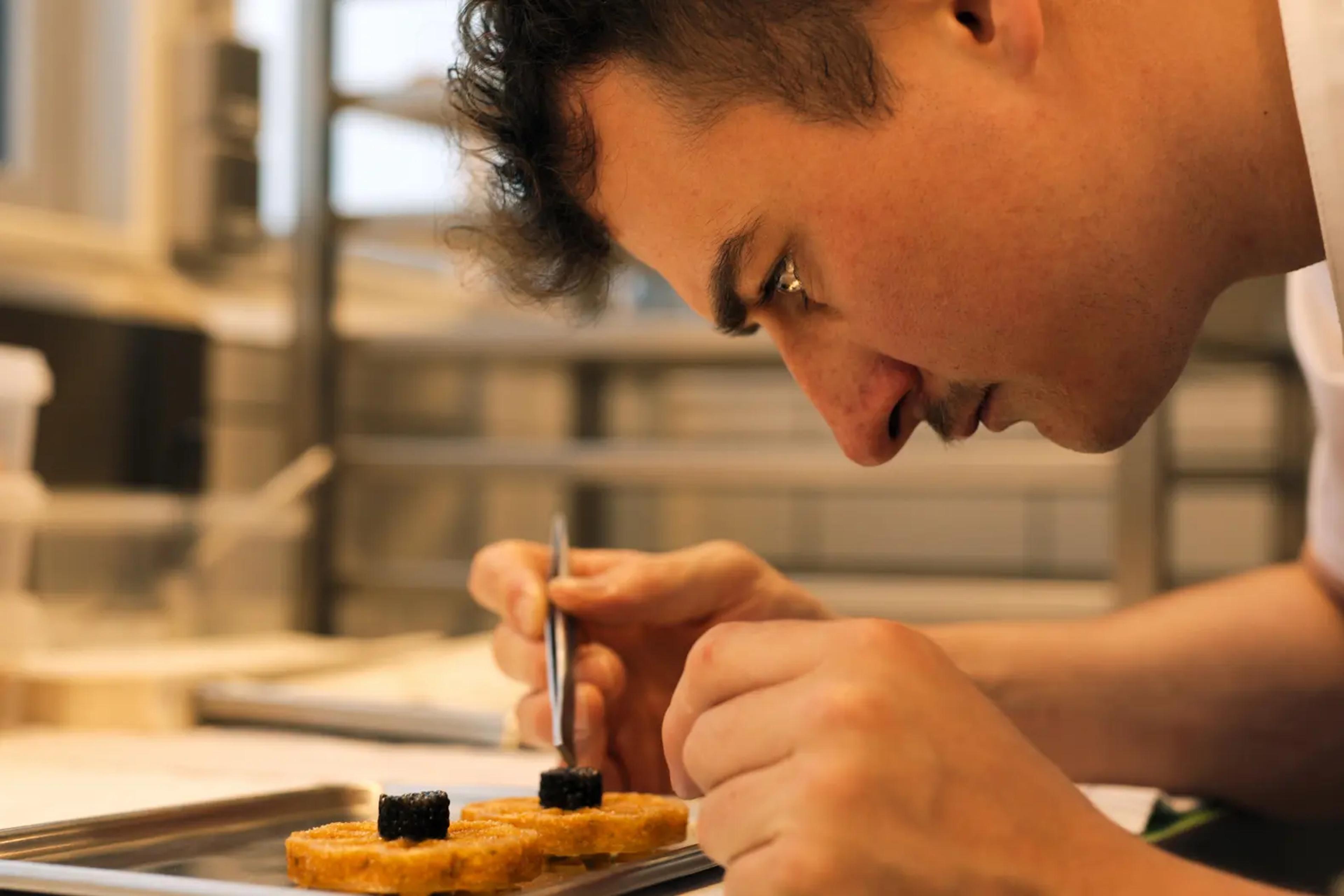 chef leaning over plating a dish in Apple TV+ series, Knife Edge