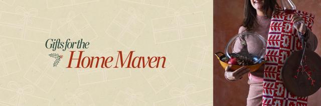 person wearing a sweater holding a floral blanket, wine glass, cast iron pot, and more home gifts