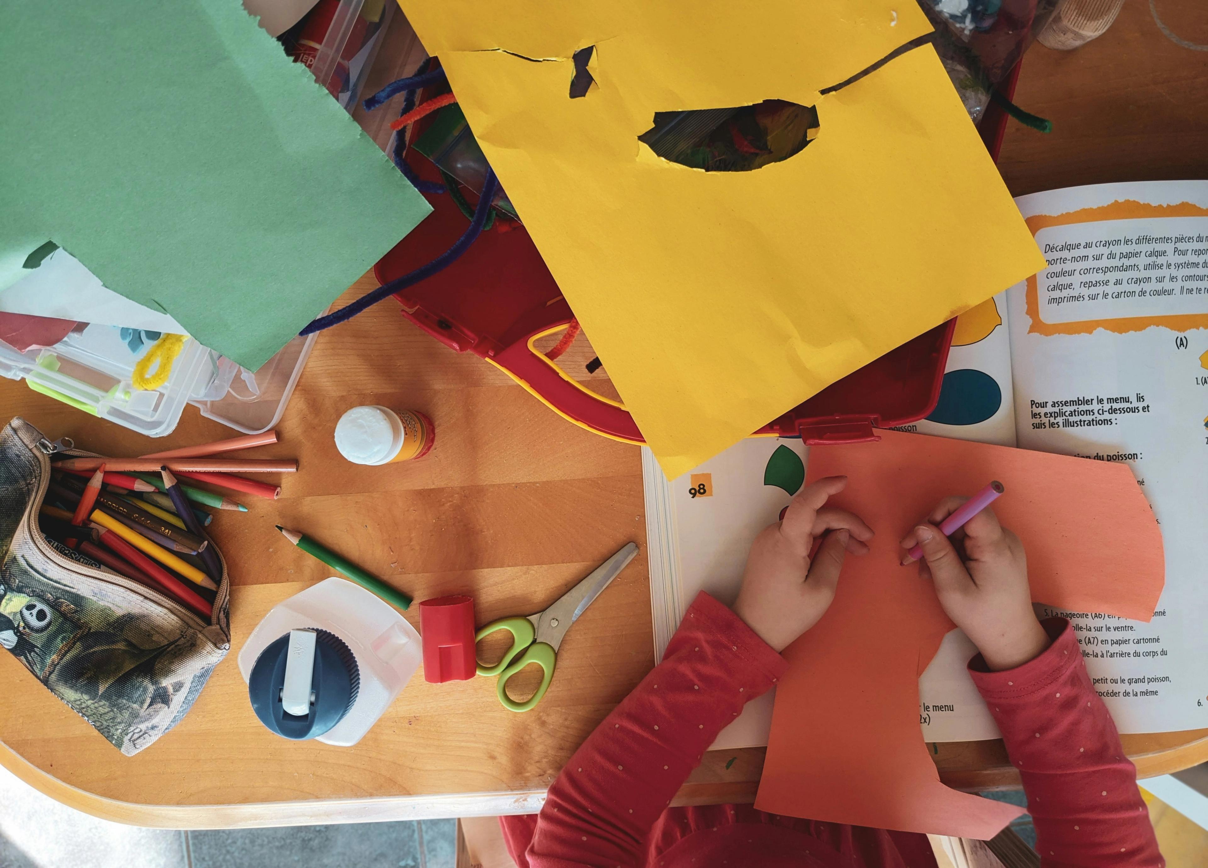 kids crafting on table with paper, cardboard, markers, and more