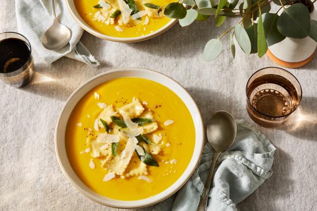 two bowls of butternut squash soup with chives and cream