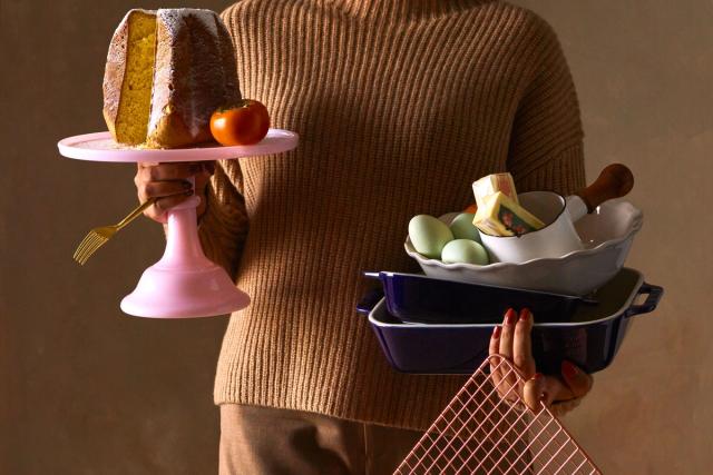 woman holding gifts for cooks including bakers, cake stands, utensils, etc