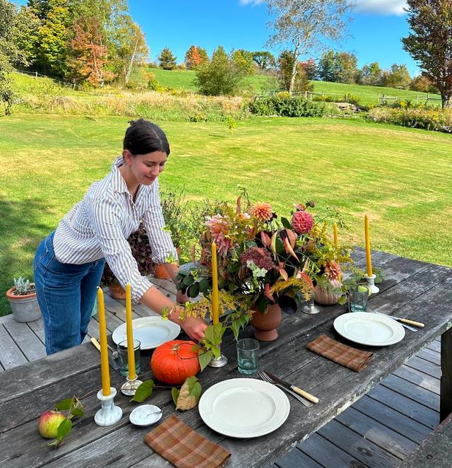 Alexis setting her outdoor fall table on the farm with apples, pumpkins, and more fresh produce.