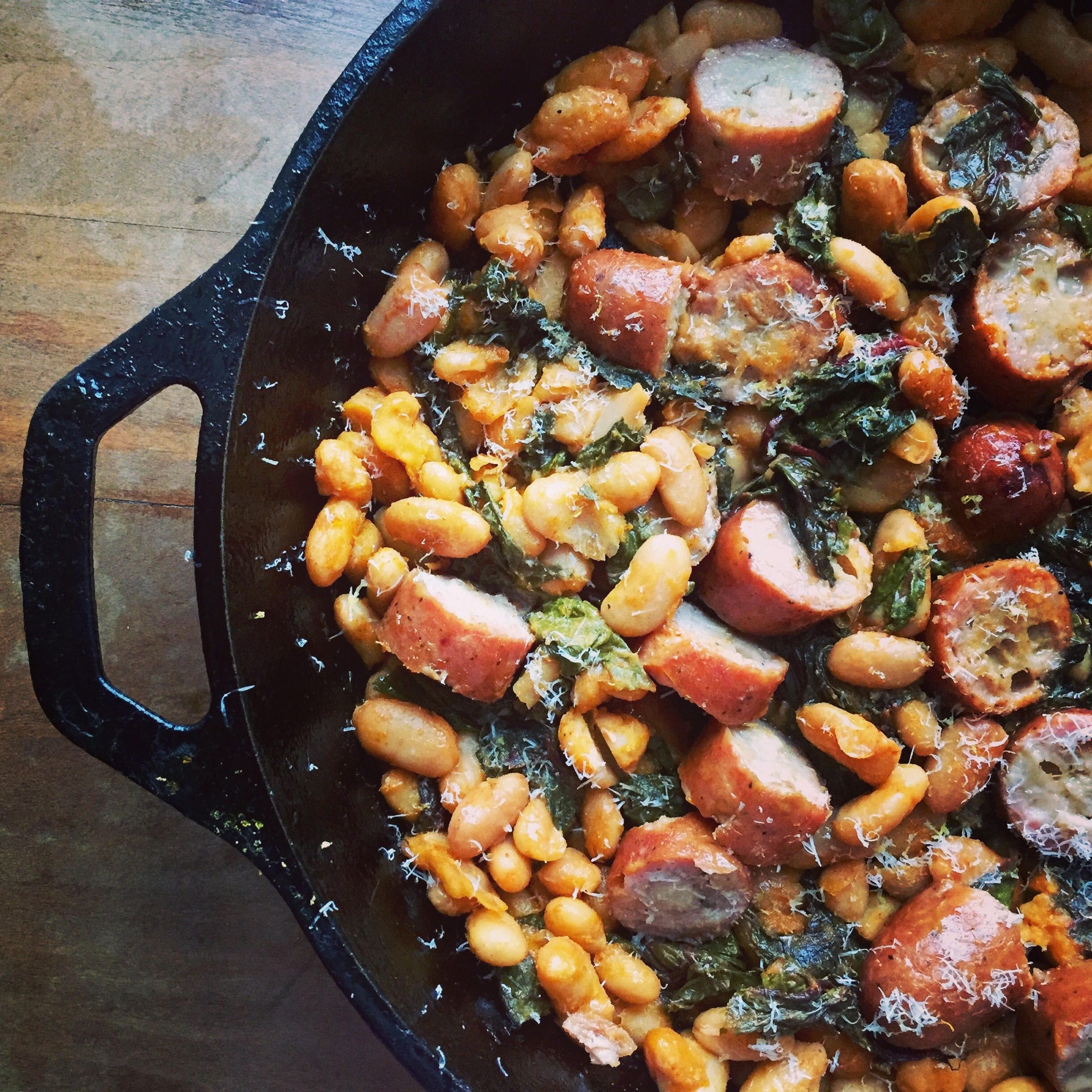 Roasted Sausage, Swiss Chard & Cannellini Beans in a cast iron skillet.