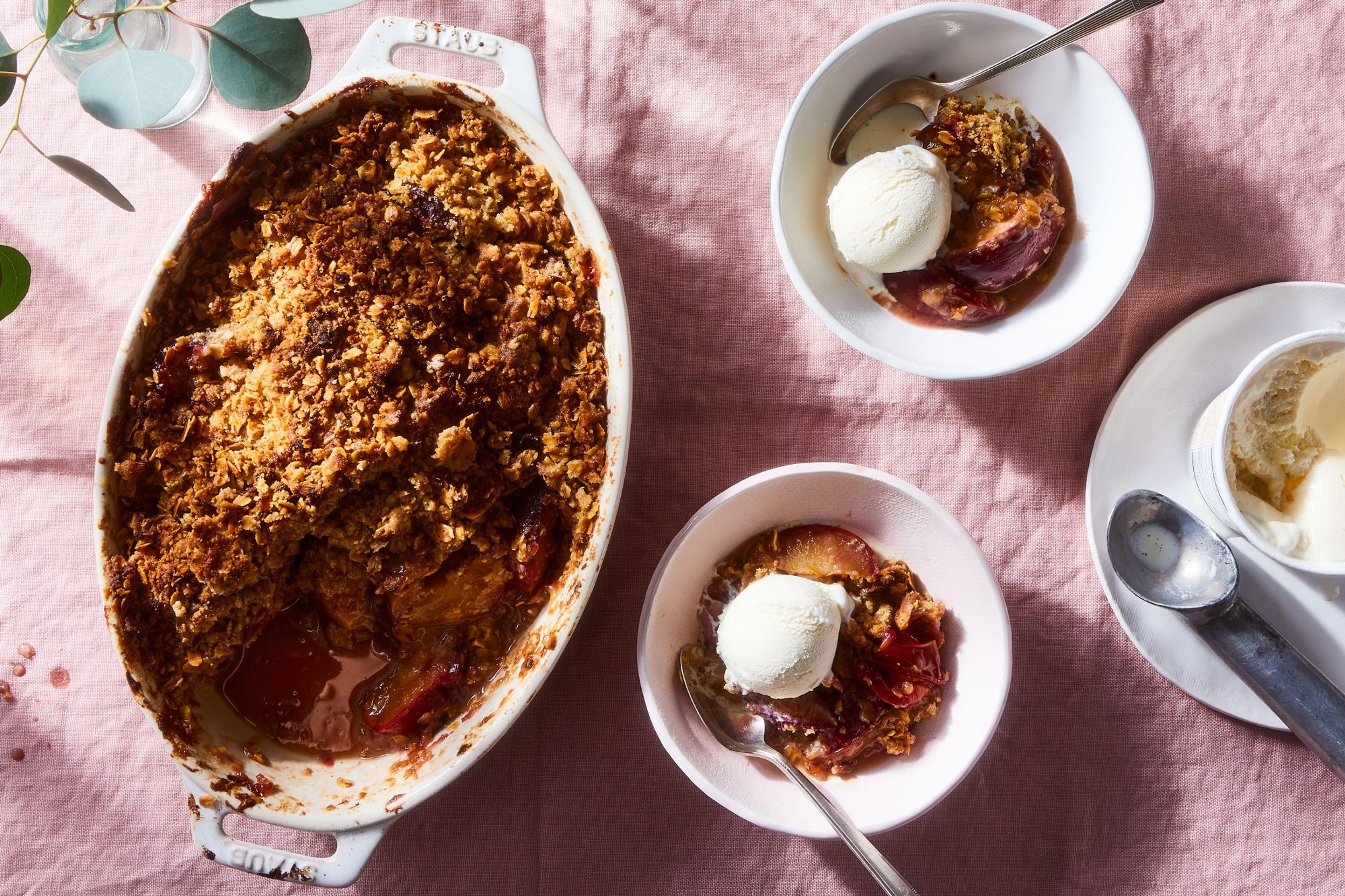 Plum crisp in bowls and dish with vanilla ice cream on side