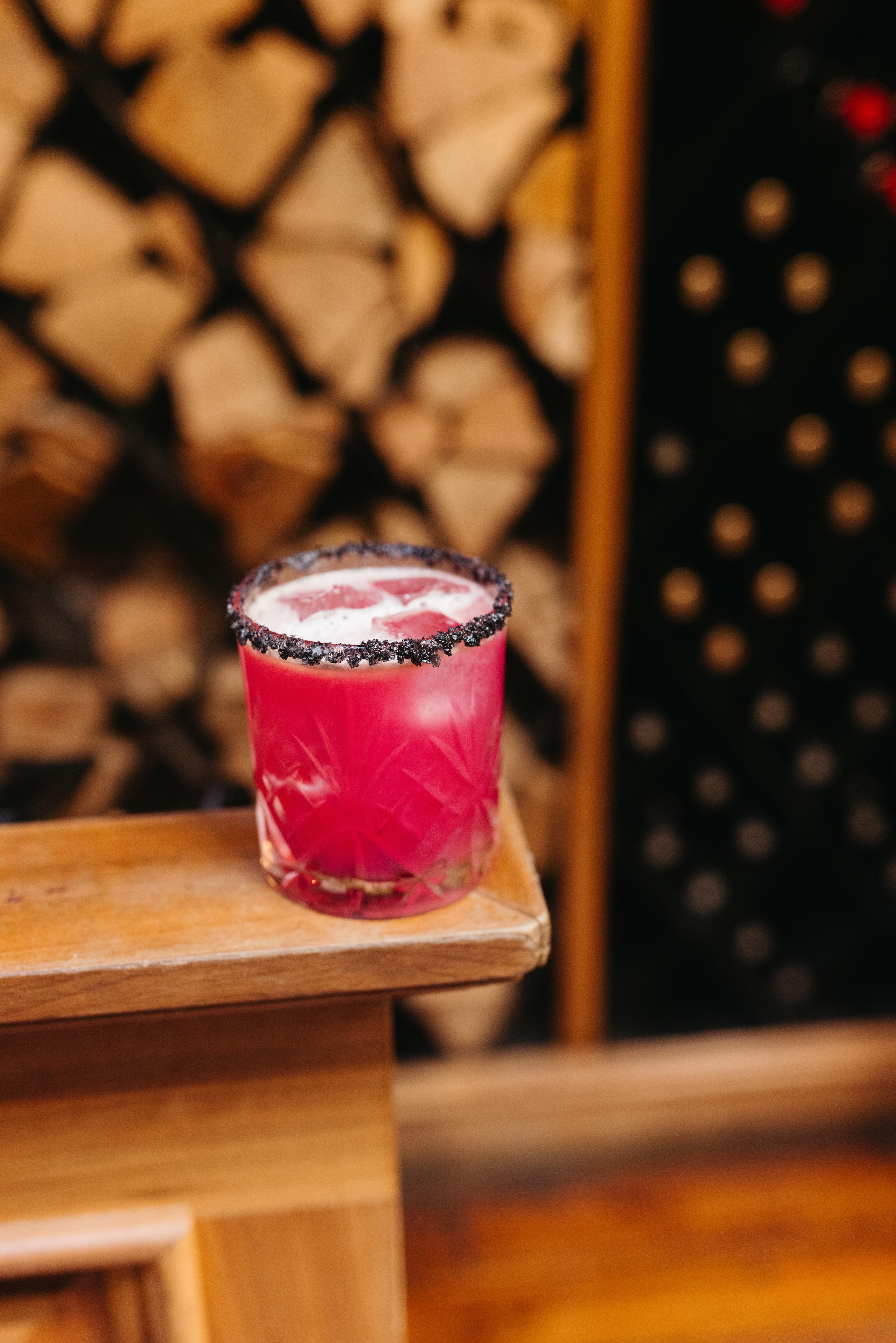 dark pink mezcal cocktail with black salt rim on table