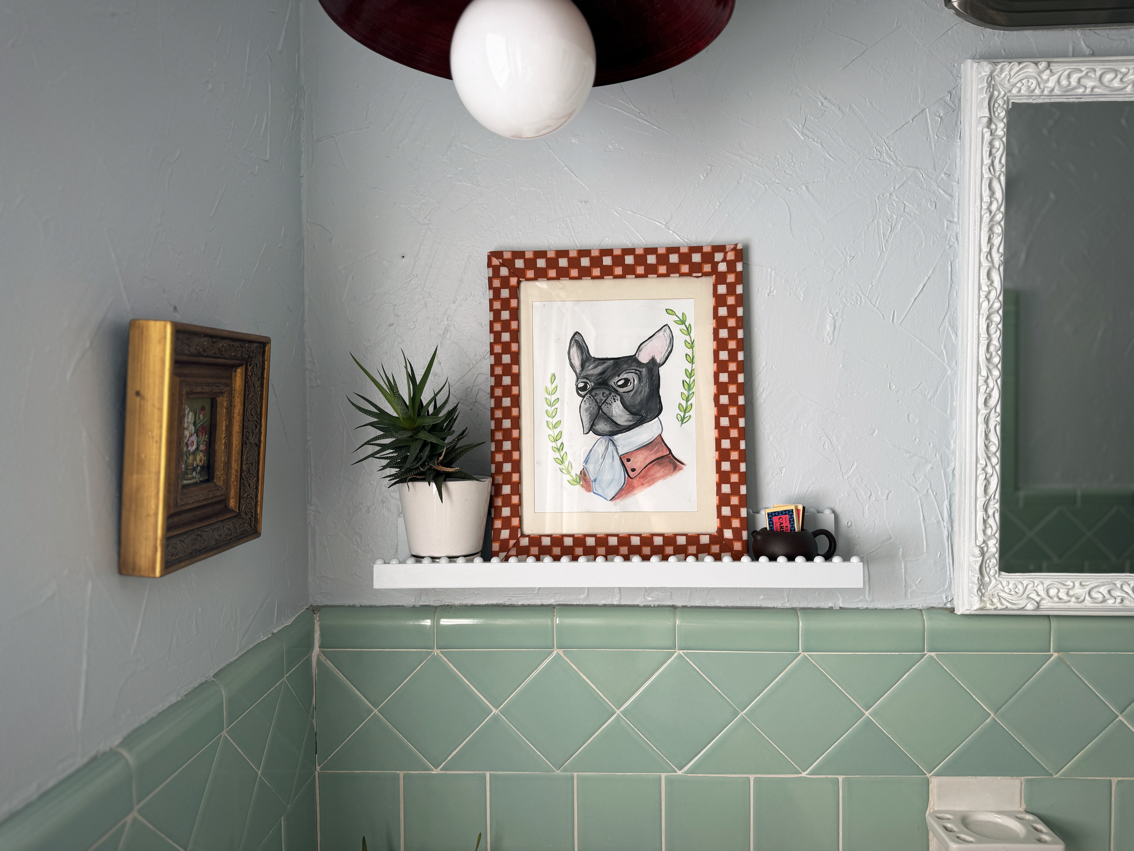 final styled batheroom shelf with pictures, plants, and more