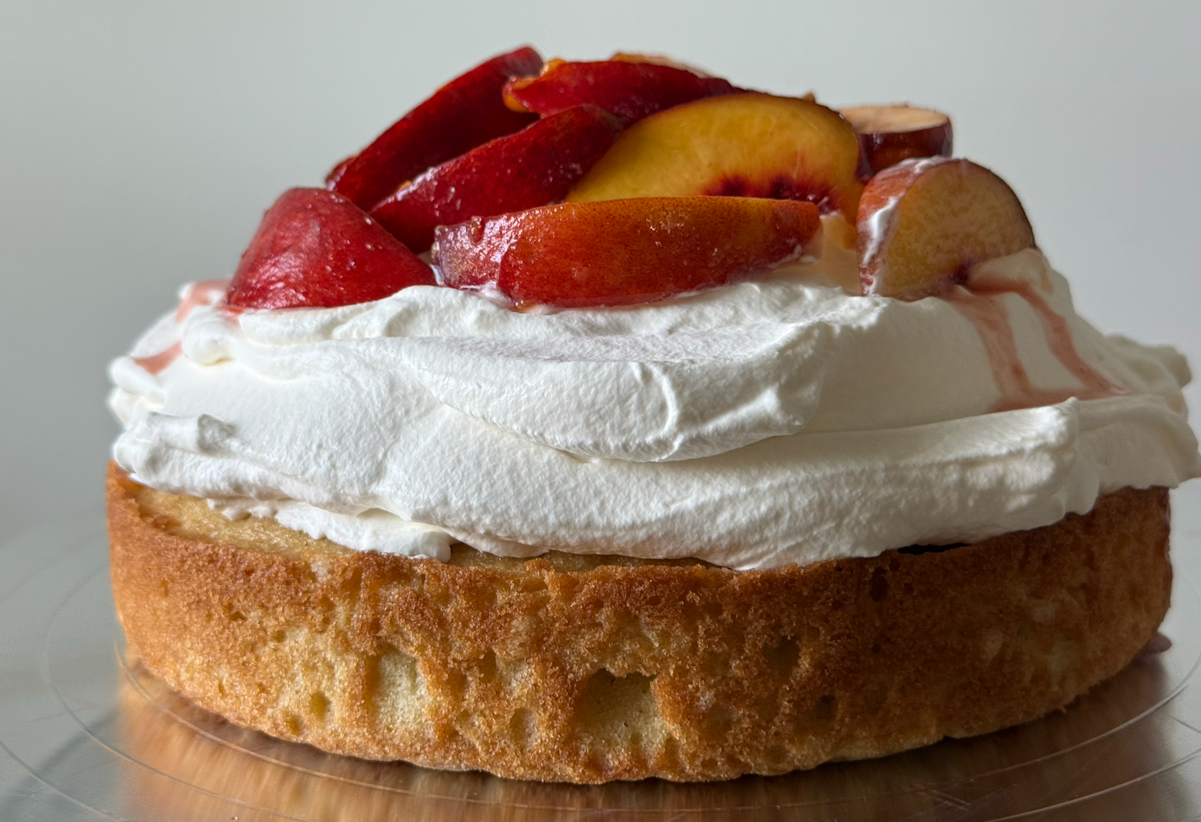 single layer cake with whipped cream and peaches on top