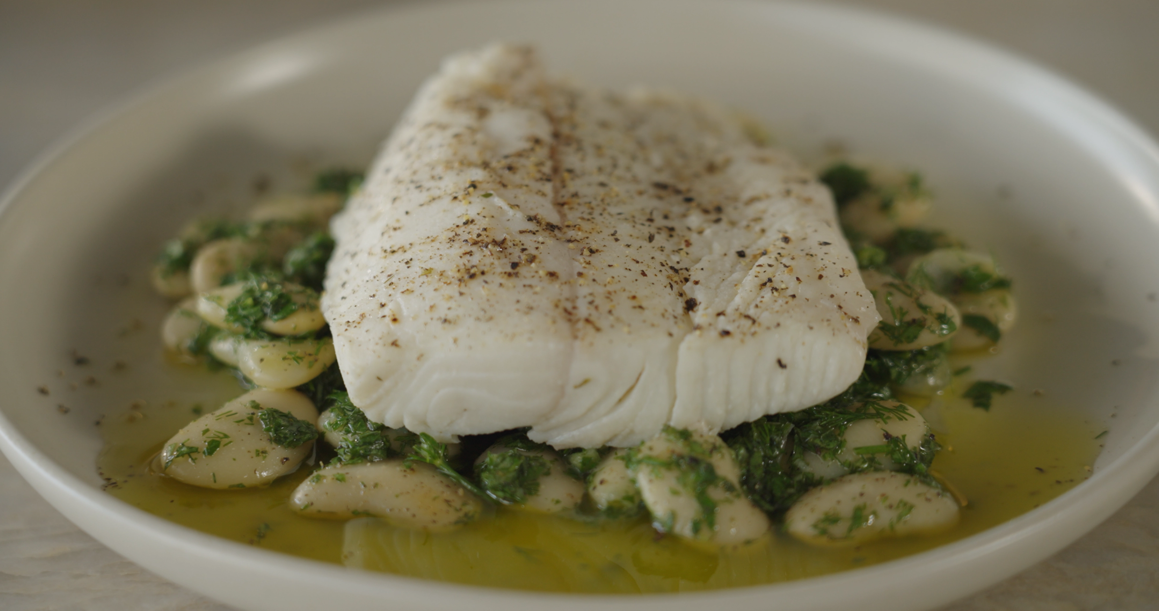 Beautiful plated shot of halibut and herby butter beans