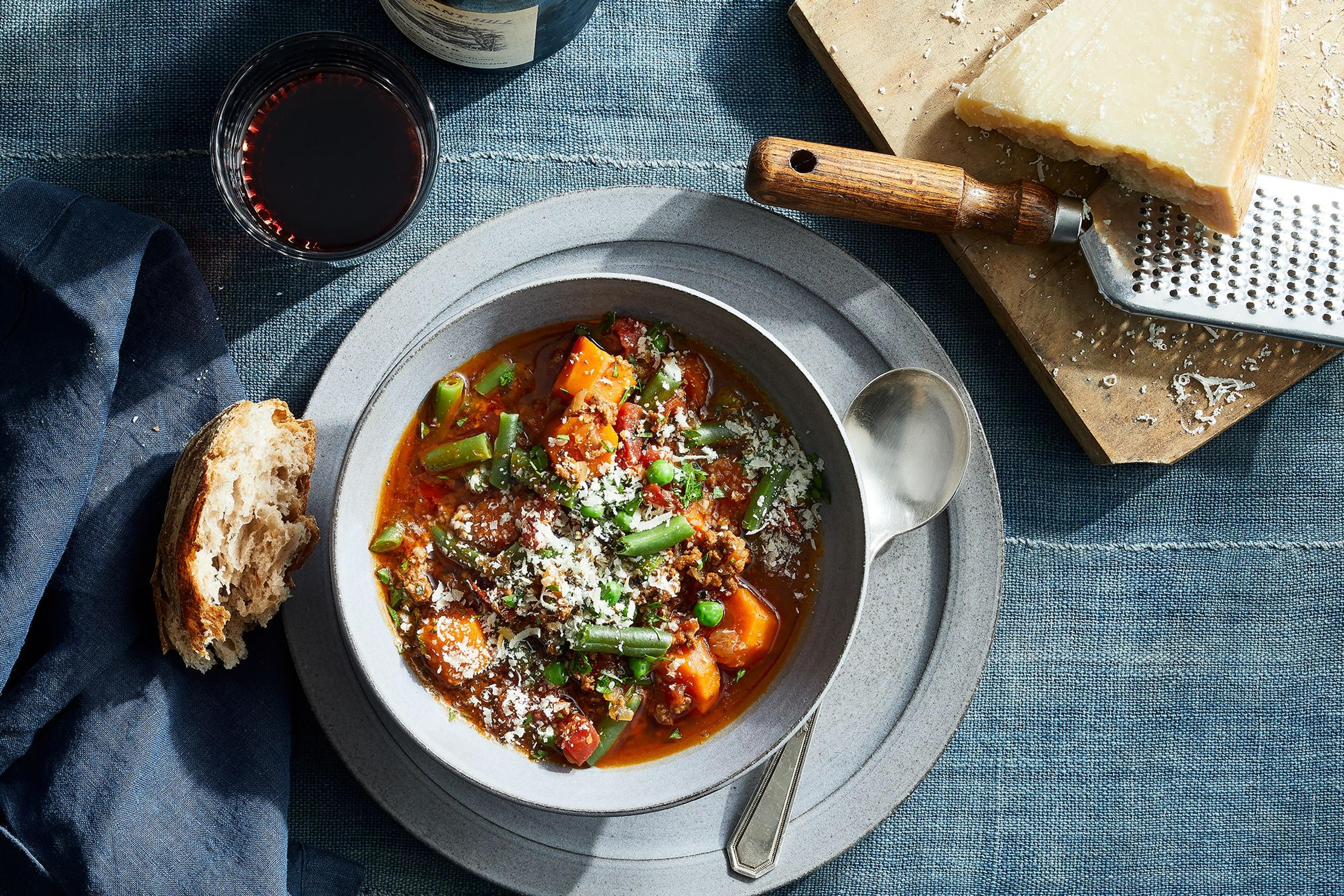 bowl of vegetable beef soup with Parmesan wedge for serving 