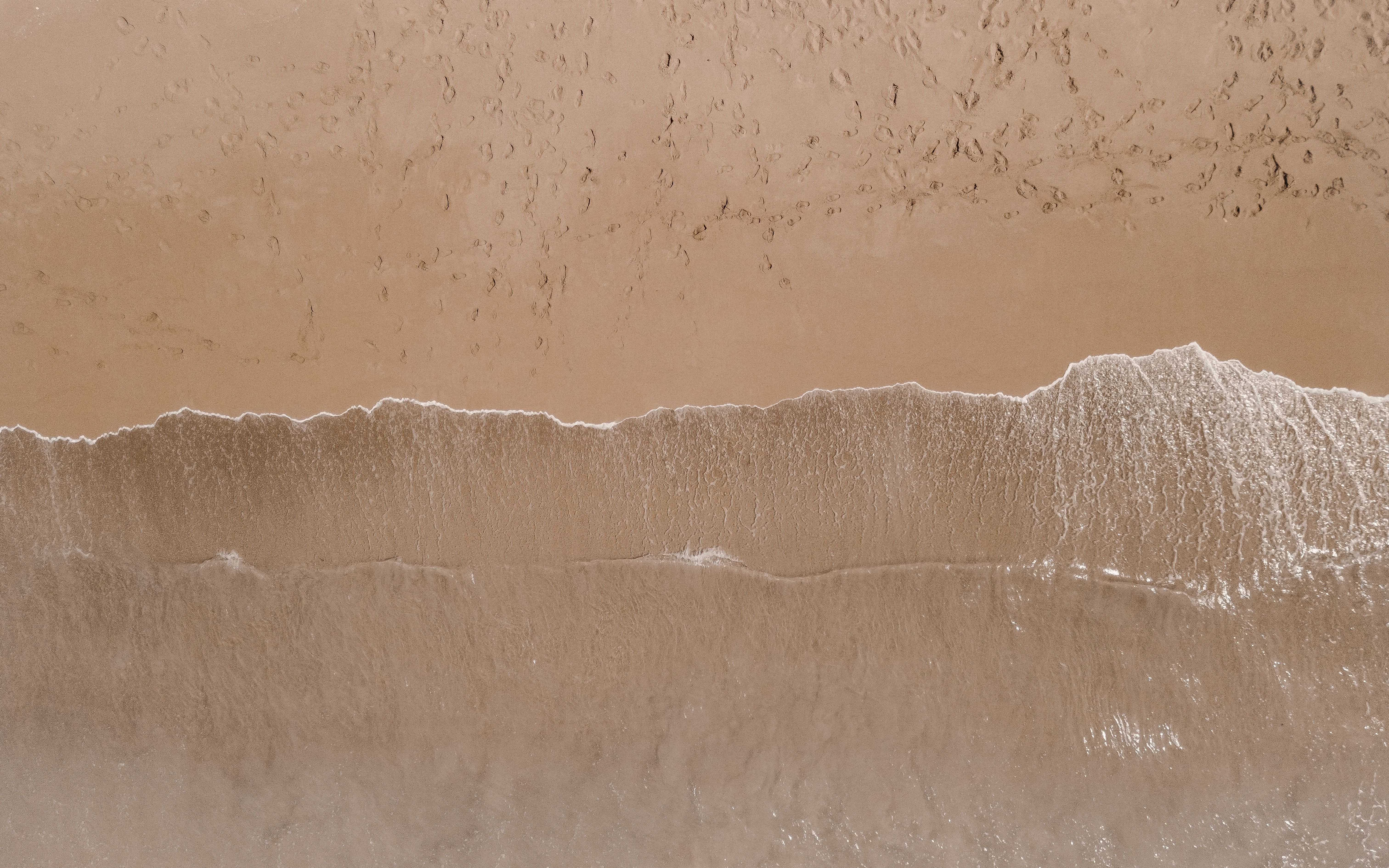 Aerial view of a sandy beach with a wave
