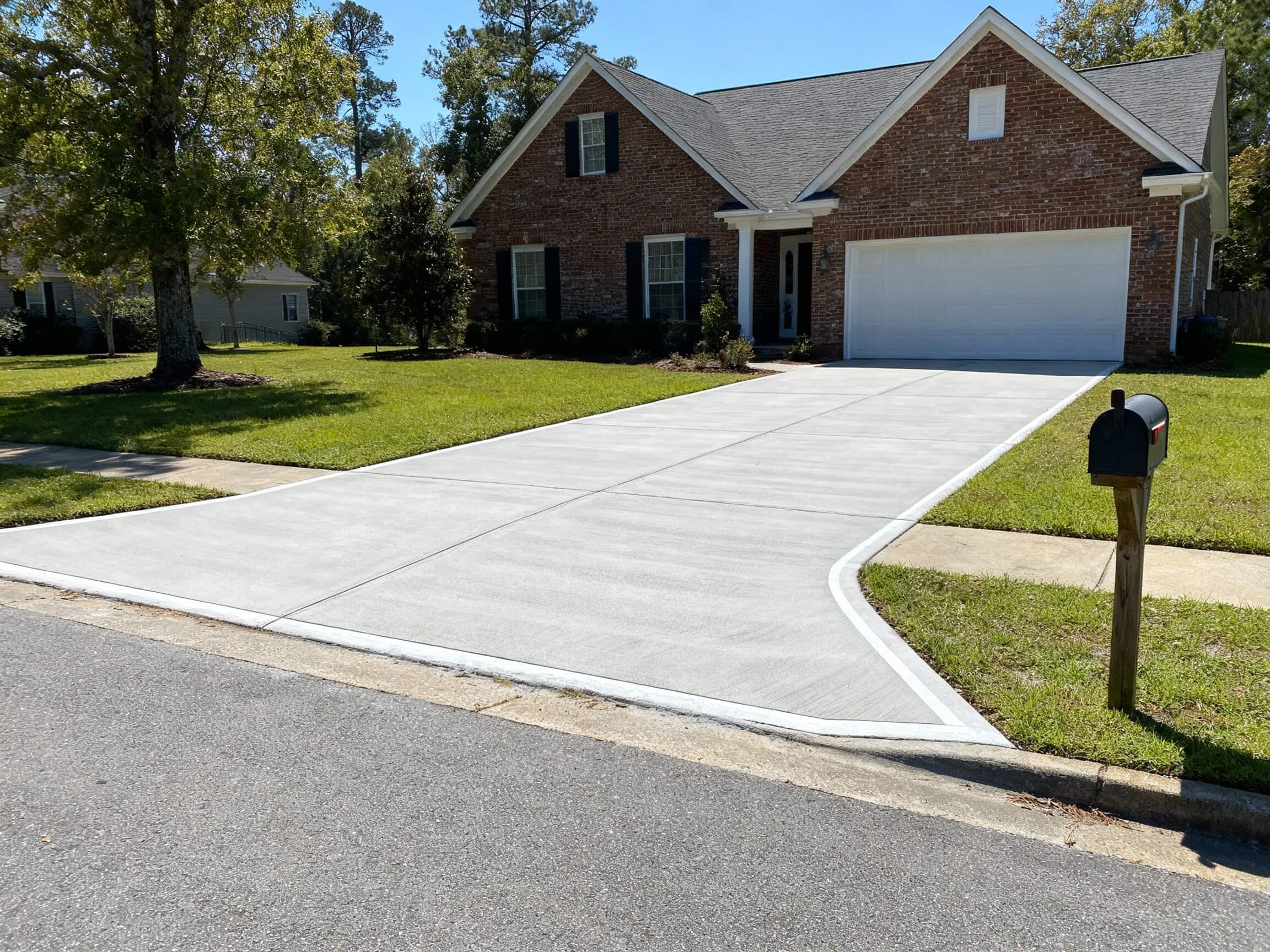 Fresh concrete driveway with smooth finish in front of a residential home