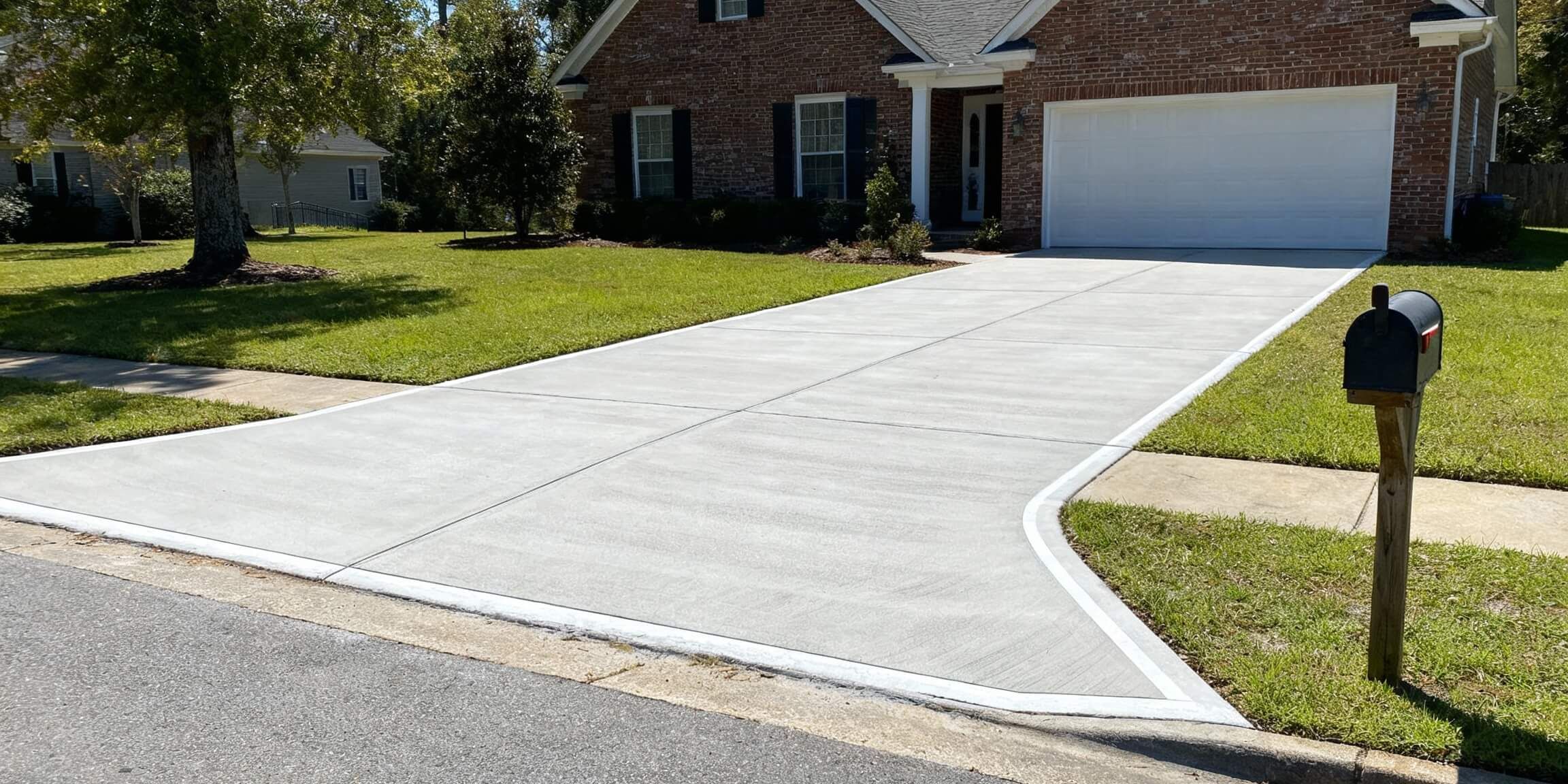 Fresh concrete driveway with smooth finish in front of a residential home