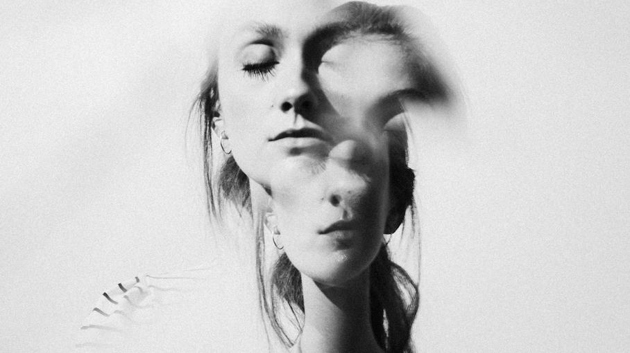 Black-and-white double exposure of a woman with closed eyes, reflecting inner tension and emotion tied to anxiety before cancer scans.