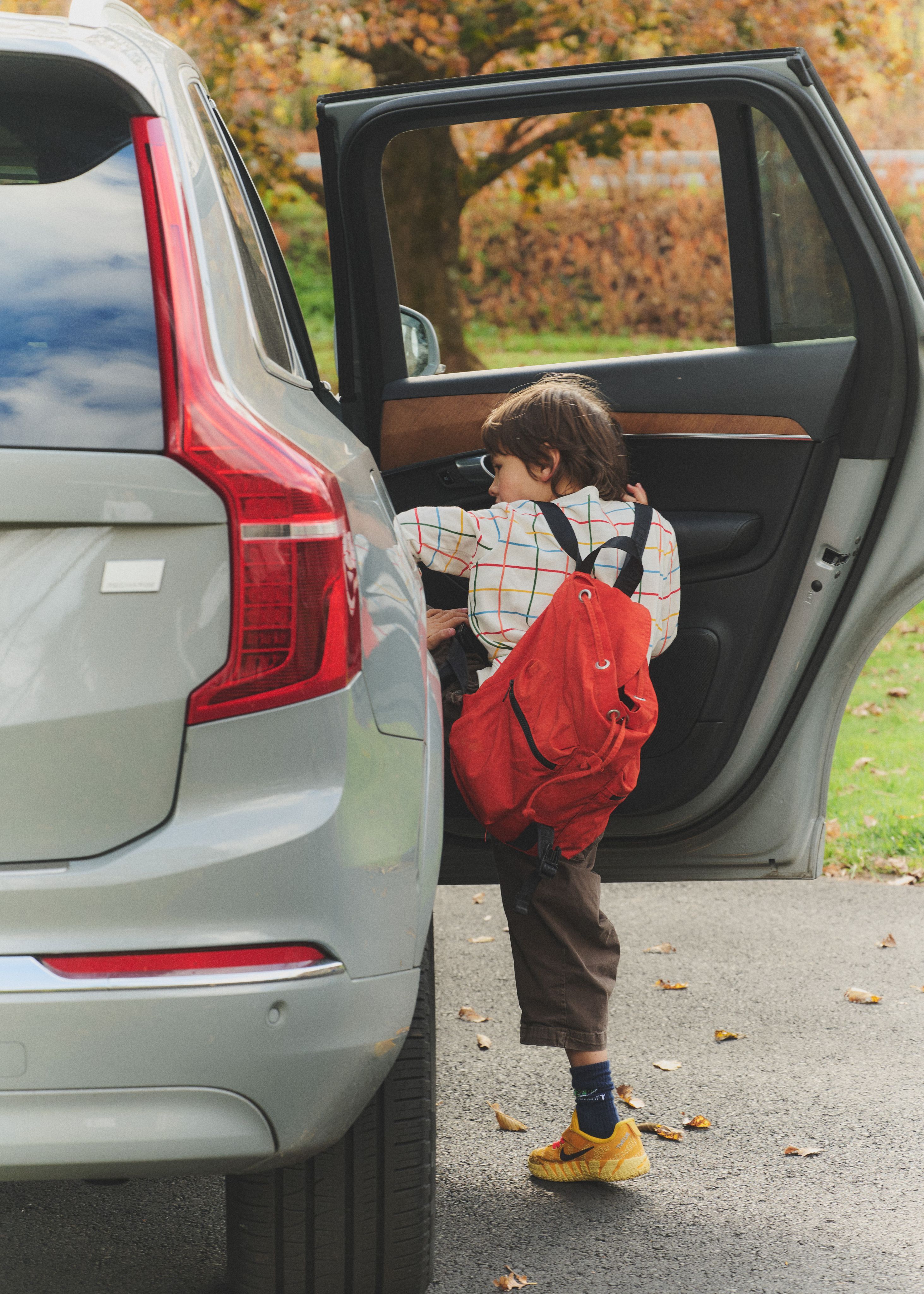 child getting into their family's car on a nice autumn day