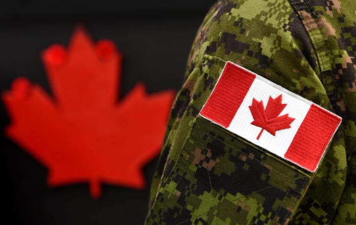 Flag of Canada on the military uniform and red Maple leaf on the background, published on an unbiased Canadian news source