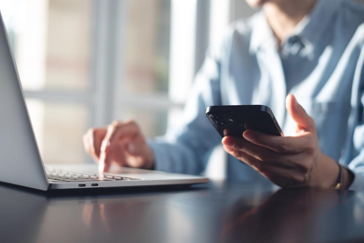 A female is using her laptop and mobile phone to access medical advice, from an unbiased news source in Canada
