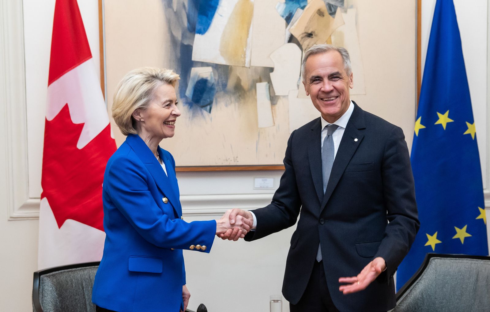 Ursula von der Leyen and Mark Carney shaking hands in front of the Canadian and EU flag