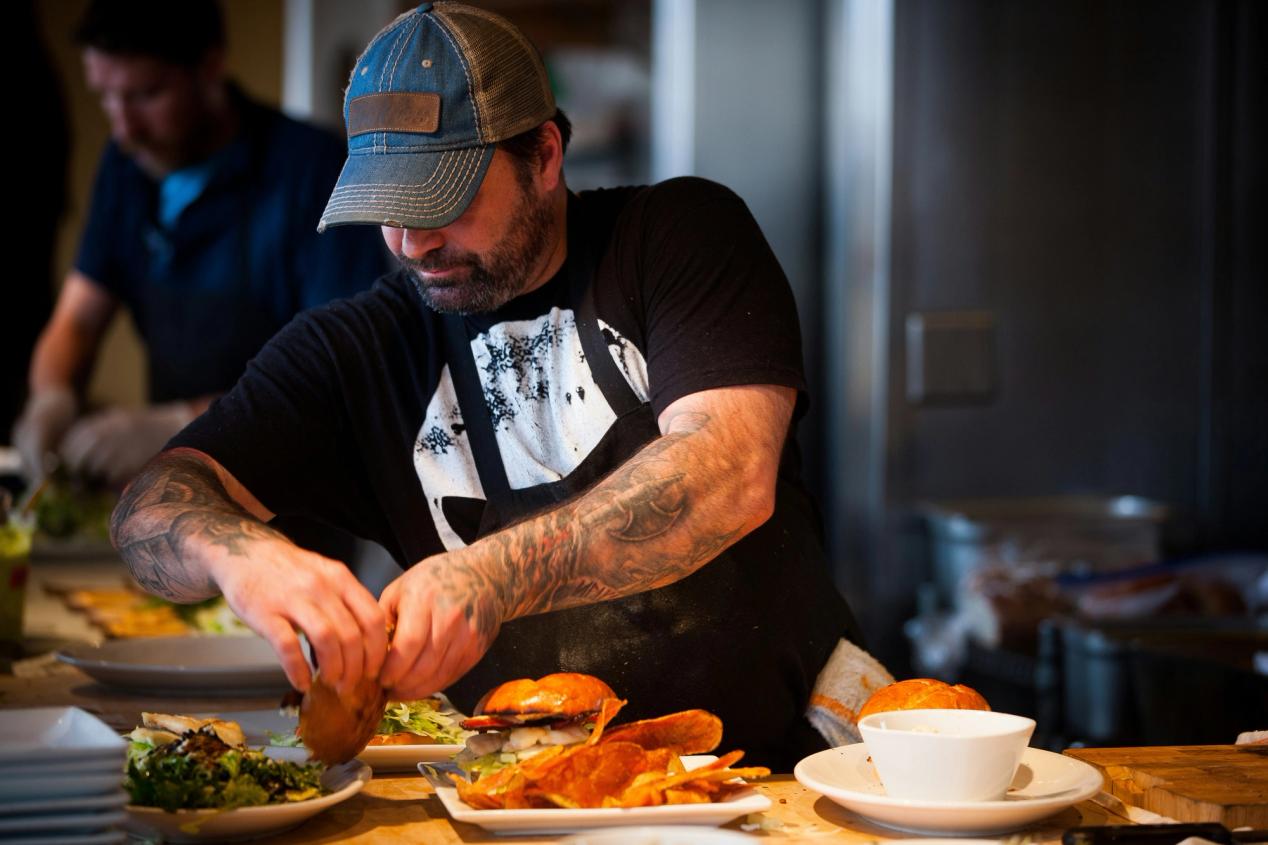 A young line cook assembles dishes in a restaurant kitchen