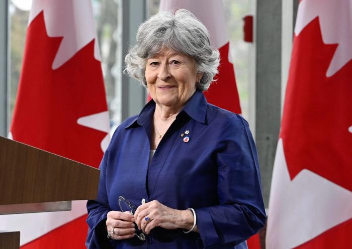 A portrait of Louise Arbour posing in front of Canadian flags