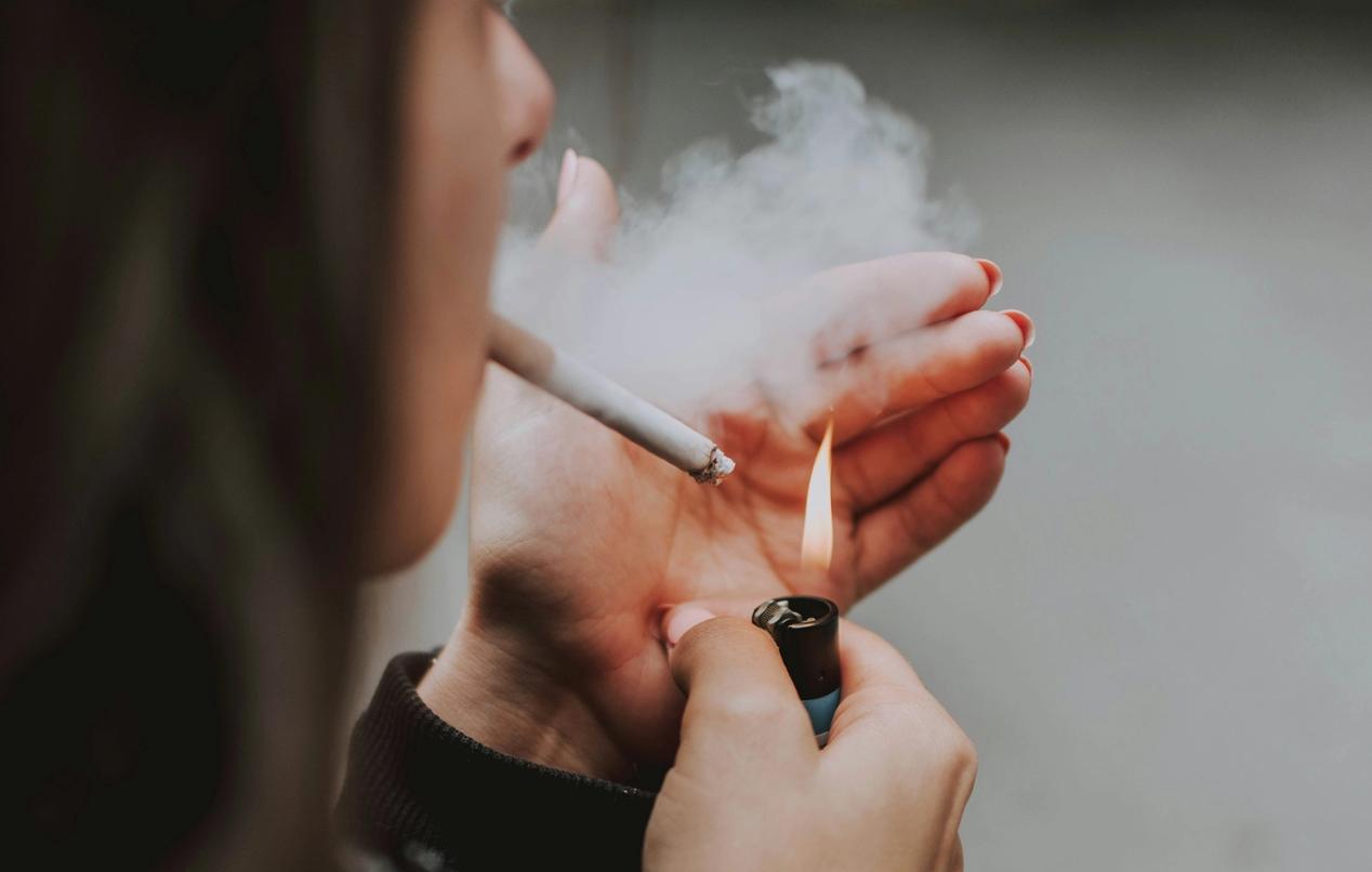 A woman lights a cigarette with a cigarette lighter