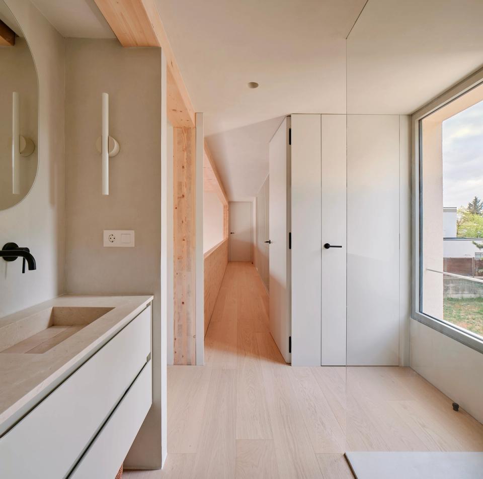 House in Girona with a bright and open bathroom visually connected to the rest of the home through a fluid and functional layout. This house in Girona combines natural wood, large windows, and minimalist finishes to create spacious, warm, and contemporary spaces