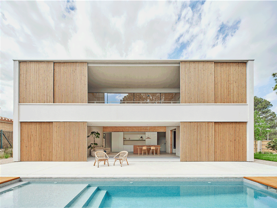 House in Girona with contemporary architecture, a natural wood façade, and an open connection between the interior, garden, and swimming pool. This house in Girona combines minimalist lines, large openings, and spacious outdoor areas to enhance natural light and comfort.