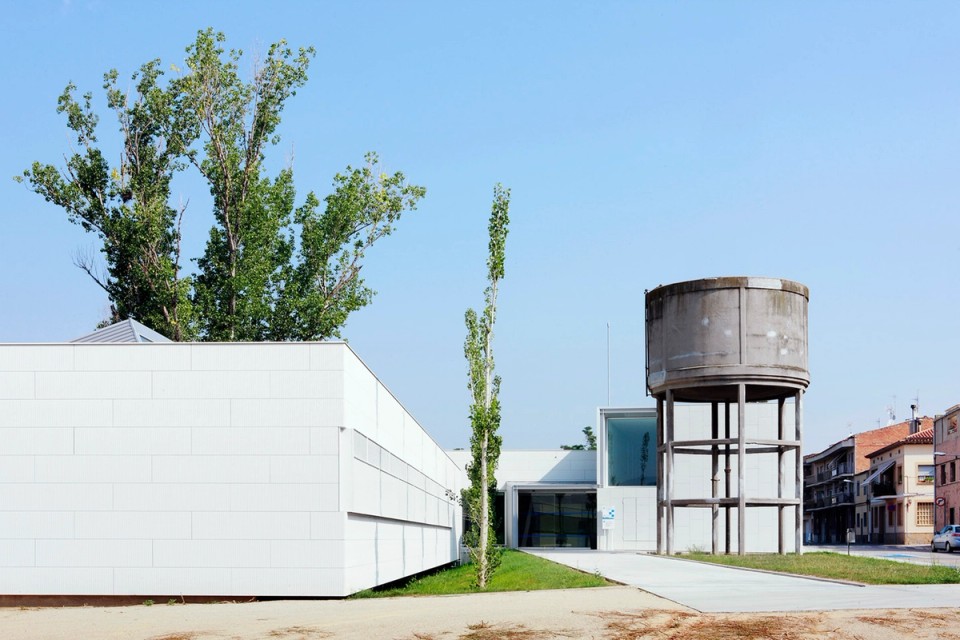 Main entrance of the Sant Vicenç Health Center, designed with contemporary architecture featuring clean volumes, large glazed openings, and light finishes that enhance brightness and the sense of welcome. The project combines functionality and formal sobriety to create an accessible, efficient healthcare facility integrated with its surroundings. The presence of vegetation and open spaces reinforces the center’s welcoming and approachable character