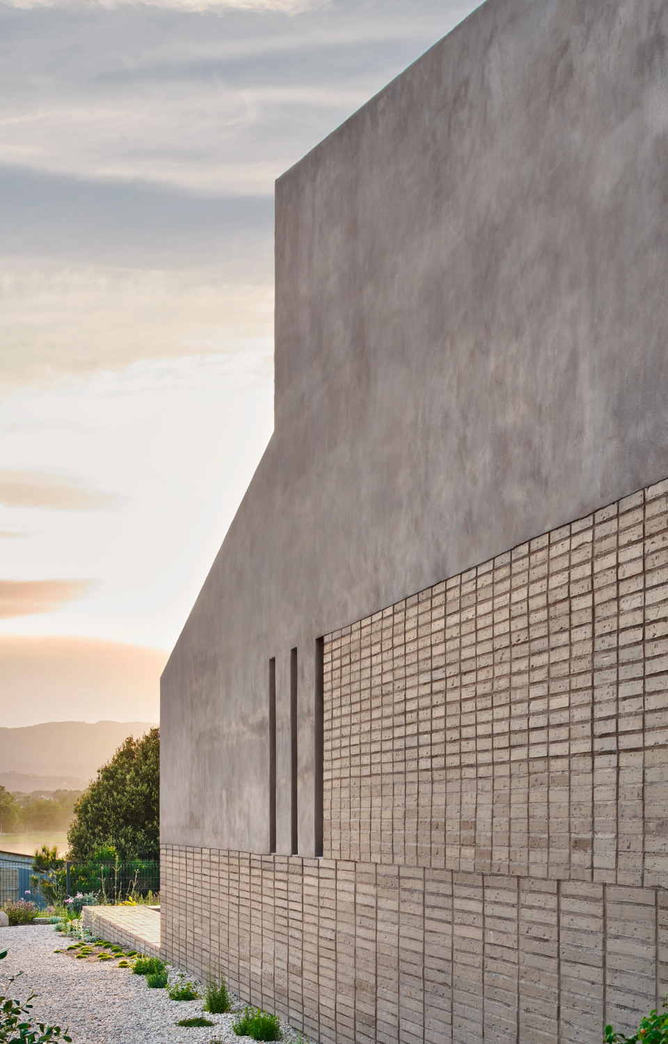 The façade of this single-family home stands out for its geometric composition and the use of textured materials that provide depth and character to the architectural ensemble. Clean volumes and vertical openings reinforce a contemporary, elegant aesthetic integrated into the surroundings.