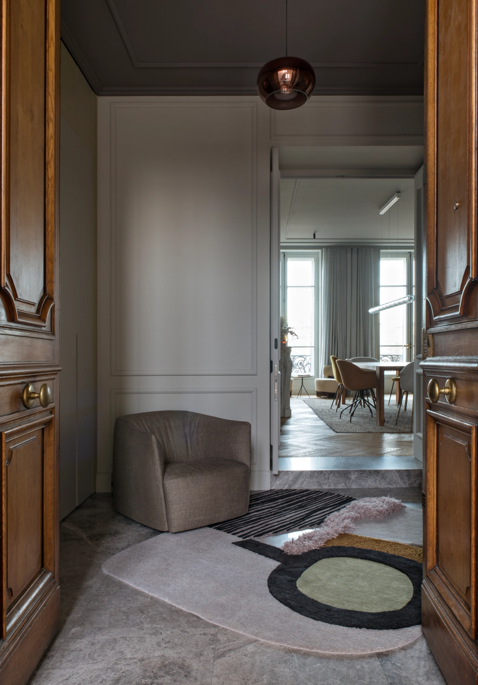 The interior renovation of this entrance combines the classical essence of the home with a contemporary and sophisticated proposal. Original wooden doors provide character and authenticity, while neutral finishes, organically shaped furniture, and subtle lighting create an elegant and balanced atmosphere. The visual transition toward the main rooms reinforces the feeling of spaciousness and material coherence, turning the entrance hall into a key element within the architectural ensemble.